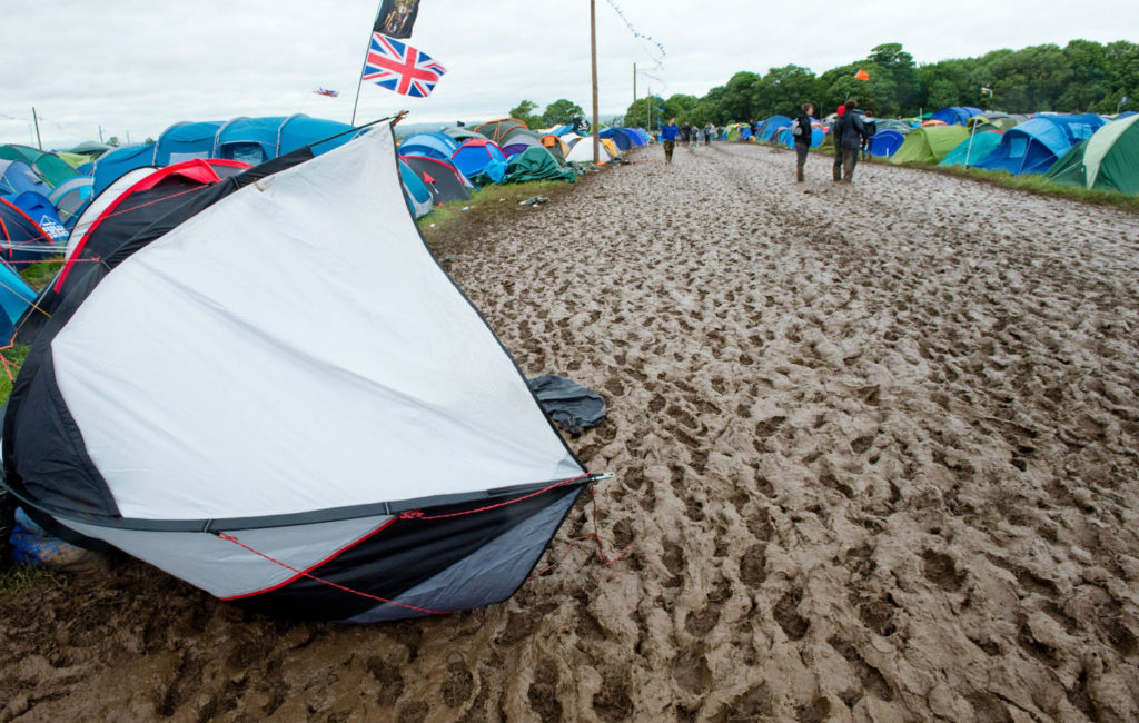 Abandoned tent next to a muddy walkway with a Union Jack flying in the background