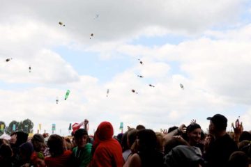 crowd of people at a music festival throwing bottles